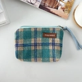 Detail van geruite canvas portemonnee met lederen label en blauwe geweven polsband - Wollen Meer Groen Blauw Geruit