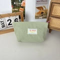 Close-up of light green fabric mini makeup bag with zip closure in a cozy home setting - Bean Green