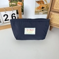 Nahaufnahme der kleinen dunkelblauen Nylon-Kosmetiktasche mit weißem Sticketikett - Marineblau