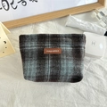 Detail van de minimalistische geruite make-uptas met bruin leren label op wit kleed - Wollen Blauw Groot Geruit