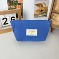 Blaue Nylon-Kosmetiktasche für Lippenstift auf einem Schreibtisch mit Dekoration gezeigt - Königsblau