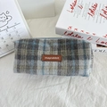 Detail van een wollen geruite etui met een leren label en een zachte textuur - Wollen Blauw Grijs Geruit