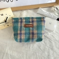 Detailed close-up of blue and beige plaid knit makeup bag with premium leather brand logo - Woolen Lake Green Blue Plaid