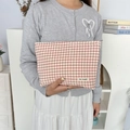 Rood-wit geblokte stoffen make-up tas vastgehouden door model in minimalistisch décor - Rood Geruit