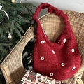 Nahaufnahme der roten Plüschtasche mit weißen Blumenapplikationen auf einem Holzstuhl - Kordelzug 3D Blume-Weinrot