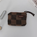 Macro shot of plaid cosmetic pouch with leather tag showing zipper and texture details - Embossed Brown