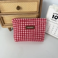 Nahaufnahme der roten karierten Woll-Kosmetiktasche mit Lederetikett auf Holztisch - Wolle Quadrat Rot Karo