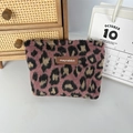 Macro-opname van roze pluche make-uptas met luipaardprint en geweven merklabel - Wollen Roze Panterprint