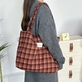 Classic red plaid wool tote bag worn by a model in a minimalist home setting - Wine Red Plaid