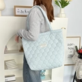 Gros plan d'un sac cabas matelassé bleu clair avec texture douce et étiquette décorative - Bleu Gourde Matelassé