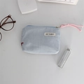 Blau gestreifte Kosmetiktasche aus Stoff mit Lippenstift und Zubehör auf dem Tisch - Blau Gestreift Roter Bogen