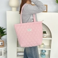 Détail du sac fourre-tout rose matelassé avec motifs ronds et étiquette en tissu blanc - Matelassé Gourde Rose