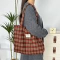 Classic red and green plaid woolen tote bag with white woven label on model's shoulder - Woolen Red Plaid