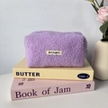 Détail de la trousse en polaire violette avec texture douce et étiquette brodée - Violet