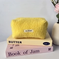 Détail de la trousse jaune en polaire pelucheuse avec texture douce et étiquette blanche - Jaune
