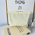 Close-up of yellow canvas makeup bag with woven label on a minimalist setup - Beige