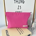 Primer plano de bolsa de cosméticos de lona rosa con etiqueta May Rabbit en un mueble - Rosa Roja