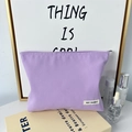 Detailed view of purple canvas makeup bag with durable zipper and brand label - Purple
