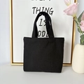 Detail of minimalist black canvas tote bag showing durable fabric texture and sturdy handles - 12oz - Open Style / Black