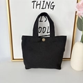 Detail of a black canvas mini handbag featuring a golden snap button and dual handles - 12oz - Snap Button Style / Black