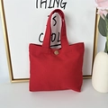 Detail view of red canvas tote bag with vintage metal button on white tabletop - 8oz - Snap Button Style / Red