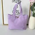 Close-up of purple canvas tote bag with a bronze snap closure on a white table - 8oz - Snap Button Style / Purple