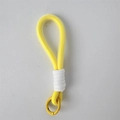 Detalle macro del llavero de cuerda trenzada amarilla con cordón decorativo blanco - Cordón Dorado