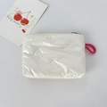 Detail of white glossy pouch featuring bow embossing and a pink lanyard strap - Small Bowknot Cream White