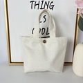 Detail of off-white thick canvas tote bag featuring a vintage bronze metal snap button - 12oz - Snap Button Style / White