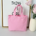 Detailed shot of a pink canvas tote bag with dual handles on a bright white tabletop - 8oz - Open Style / Pink