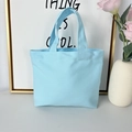 Close-up of a light blue canvas tote bag with dual handles in a minimalist home setting - 8oz - Open Style / Blue