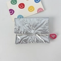 Detail of silver metallic quilted pouch with embossed bow patterns and pink elastic strap - Small Bow Silver