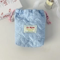 Macro shot of light blue quilted drawstring bag with heart patterns and lace detail - Blue