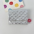 Close-up of silver quilted mini purse with glossy finish, snap button, and pink strap loop - Small Square Silver