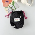 Detailaufnahme des schwarzen gesteppten Beutels mit weißen Schleifen und Kordelzug - Bestickte Schwarze Schleife