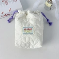 Macro detail of white heart-quilted storage bag with purple drawstring and woven label - White