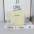 Close-up of cream canvas makeup bag with May Rabbit label and circular metal zipper - Beige