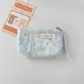 Detail of light blue fuzzy makeup pouch with gold embroidery and purple ribbon pull - Blue Daisy