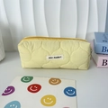 Gros plan sur la trousse matelassée jaune avec texture douce et étiquette de la marque - Matelassé Gourde Jaune