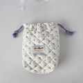 Close-up of quilted floral camera bag with purple drawstring and soft cotton texture - White Base Floral