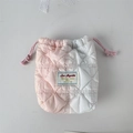 Close-up of quilted two-tone drawstring camera pouch with diamond patterns and woven label - Quilted Rainbow
