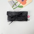 Detail of black quilted pouch featuring embossed butterfly patterns and a ribbon bow closure - Black Bow