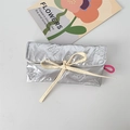 Close-up of quilted silver butterfly embossed pouch with beige bow tie and pink elastic loop - Bowknot Silver