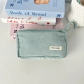 Detail of mint green corduroy pencil case with zipper, handle, and brand label on top - Light Blue Grey
