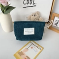Close-up of dark teal corduroy makeup bag with textured vertical stripes and canvas patch - Dark Green