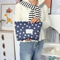 Detail of dark blue floral canvas makeup bag held by hand in a cozy lifestyle setting - Dark Blue Clover