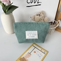 Detail view of bean green corduroy makeup bag with top zipper and white patch label - Grass Green