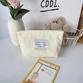 Detailopname van corduroy toilettas met metalen rits en geborduurde stoffen patch - Crèmewit