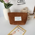 Close-up of brown corduroy makeup bag with white label and clear ribbed texture - Brown