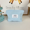 Makrodetail des blauen Waffelgewebes und des Stoffetiketts auf der Kosmetiktasche - Blau